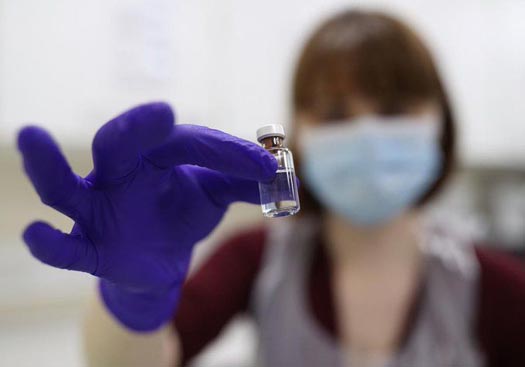 Nurse holding a small bottle containing a COVID-19 vaccine